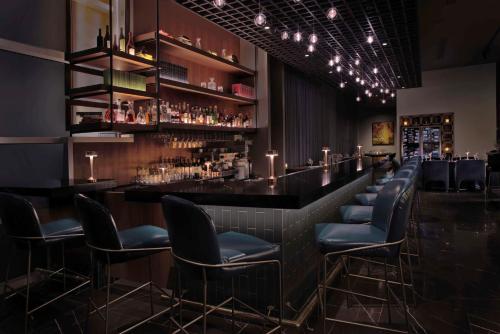 a bar with black leather chairs and lights at Hilton Omaha in Omaha
