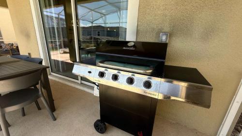 a kitchen with a grill with a table and a counter top at Upstay ChampionsGate Home w Pool BBQ & Game Room in Kissimmee