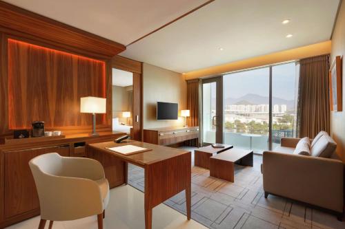 a hotel room with a desk and a couch at Hilton Barra Rio de Janeiro in Rio de Janeiro