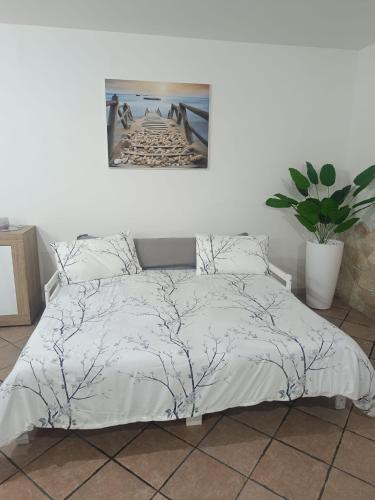 a bed with a white comforter and a plant at Home Relax di Davide e Michela in Civitavecchia