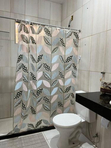 a bathroom with a shower curtain and a toilet at Natureza Viva in Camacari