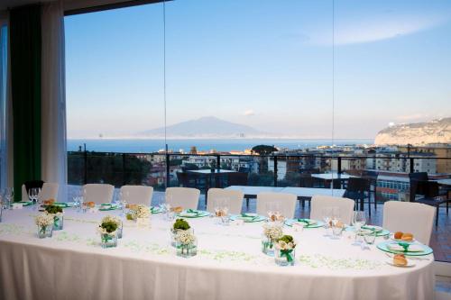 a table with white chairs and a view of the ocean at Hilton Sorrento Palace in Sorrento