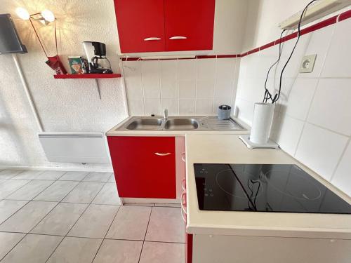 une petite cuisine avec des armoires rouges et un évier dans l'établissement Studio Cabine Centre Port pour 4 avec Parking et Animaux admis - FR-1-749-92, au Cap d'Agde