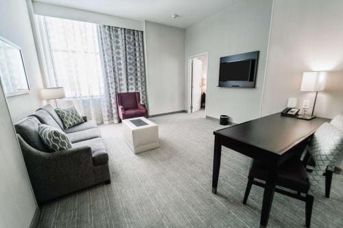 a living room with a couch and a desk in a hotel room at Embassy Suites Louisville Downtown in Louisville