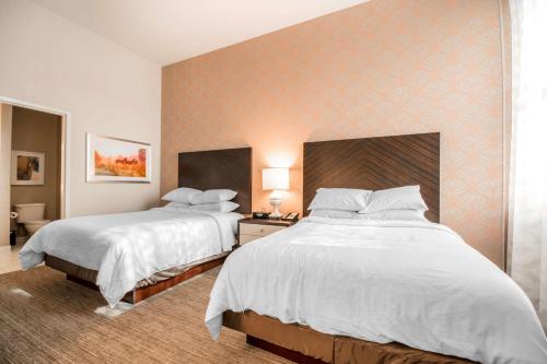 a hotel room with two beds with white sheets at Embassy Suites Louisville Downtown in Louisville