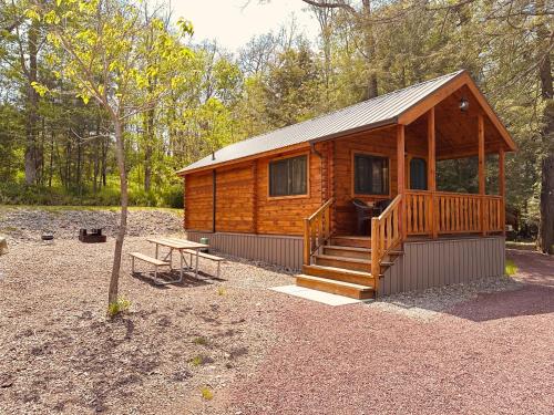 a wooden cabin with a staircase and a picnic table at Lakewood Park Campground - Luxury Cabin in Barnesville