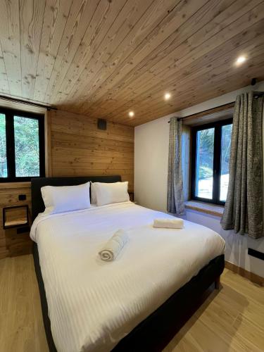 un grand lit blanc dans une pièce avec des fenêtres dans l'établissement La fruiterie, à Glières-Val-de-Borne