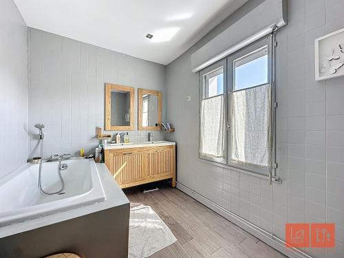 une salle de bain avec une baignoire, un lavabo et une fenêtre dans l'établissement Villa Océane, à Wimereux