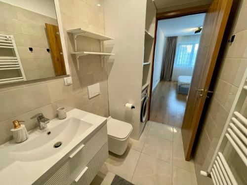 a white bathroom with a sink and a toilet at Sunrise Apartments - Onix Pipera in Bucharest