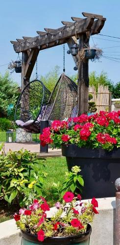 a swing in a garden with flowers and a swing at La Clé des Champs - Studio PiscineSPA-Sauna au jardin tropical idyllique et bucolique in Jouarre