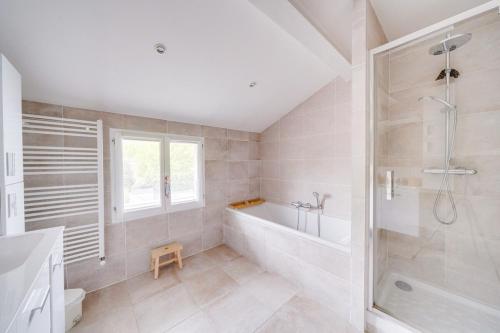 une salle de bain blanche avec une baignoire et une douche dans l'établissement Maison familiale climatisée avec piscine, à Bordeaux