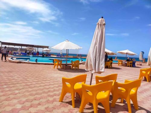 a beach with chairs and an umbrella and a pool at Chalet ElGammal in Marsa Matruh