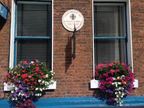 two windows with flowers and a clock on a brick building at Dergvale Hotel in Dublin