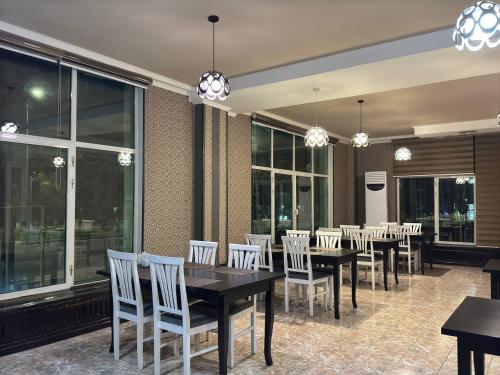 a dining room with tables and chairs and windows at Hotel Malika Tashkent in Tashkent