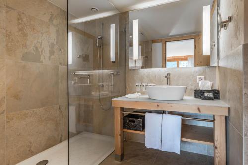 a bathroom with a sink and a shower at Hotel Spitzhorn Superieur in Gstaad