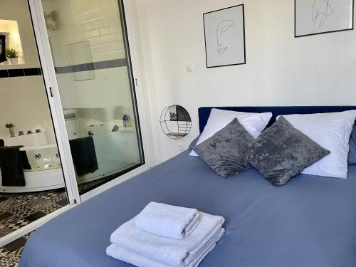 a blue bed with two pillows and towels on it at La Clé des Champs - Studio PiscineSPA-Sauna au jardin tropical idyllique et bucolique in Jouarre