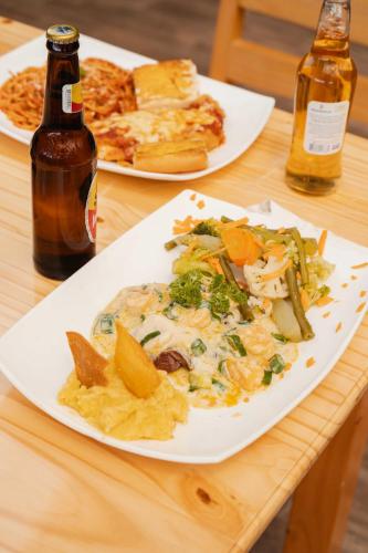 a table with two plates of food and two bottles of beer at Cabañas La Hacienda in San Pablo