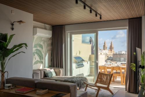 a living room with a couch and a large window at ROP Penthouse & ROF Apartment by Homega, Terrace, Private Pool & Valletta Views in Sliema