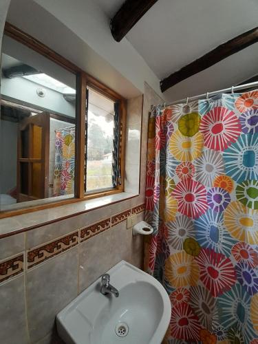 a bathroom with a sink and a window and a shower curtain at Pisonaywasi - Hospedaje familiar in Urubamba