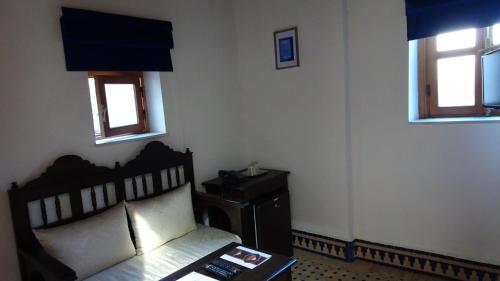a bedroom with a bed and a table and two windows at Riad Sabah in Fès