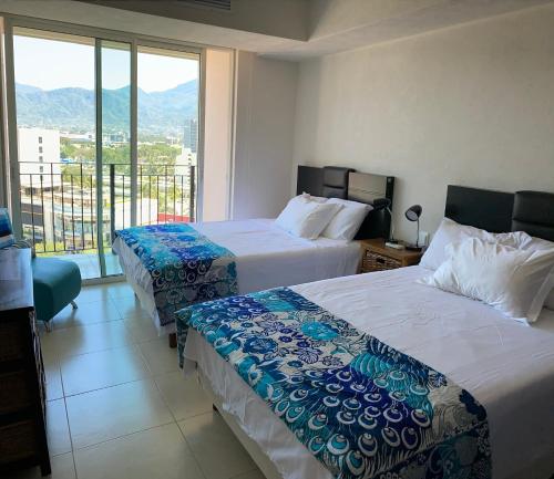 a hotel room with two beds and a balcony at Ocean front Grand Venetian corner condo in Puerto Vallarta