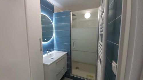 La salle de bains est pourvue d'un lavabo blanc et d'un mur bleu. dans l'établissement 3 pièces Vue Mer à 2 très proche THALASSO, à Cabourg