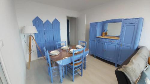 une salle à manger bleue avec une table et des armoires bleues dans l'établissement 3 pièces Vue Mer à 2 très proche THALASSO, à Cabourg