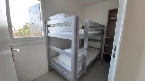 un lit superposé blanc avec des oreillers blancs et une fenêtre dans l'établissement 3 pièces Vue Mer à 2 très proche THALASSO, à Cabourg