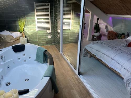 a large bathroom with a tub and a bed at La Clé des Champs - Studio PiscineSPA-Sauna au jardin tropical idyllique et bucolique in Jouarre