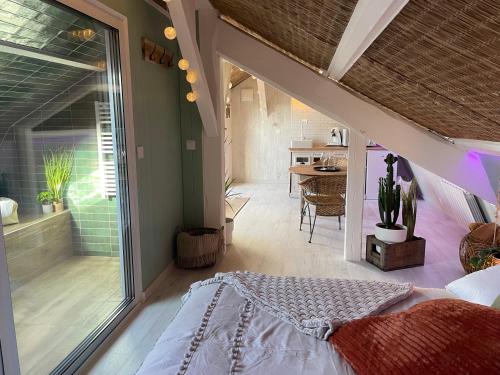 a bedroom with a bed and a large window at La Clé des Champs - Studio PiscineSPA-Sauna au jardin tropical idyllique et bucolique in Jouarre