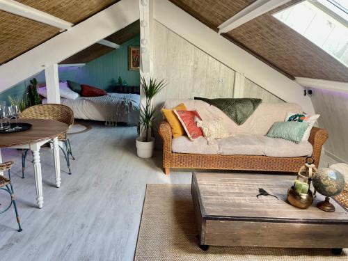 a living room with a couch and a bed at La Clé des Champs - Studio PiscineSPA-Sauna au jardin tropical idyllique et bucolique in Jouarre