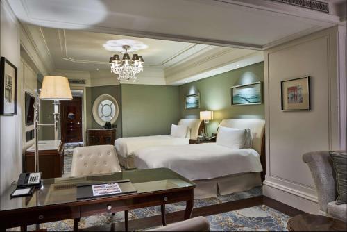 a hotel room with two beds and a desk at Waldorf Astoria Shanghai on the Bund in Shanghai
