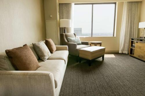 a living room with a couch and a chair and a window at Hilton Salt Lake City Center in Salt Lake City