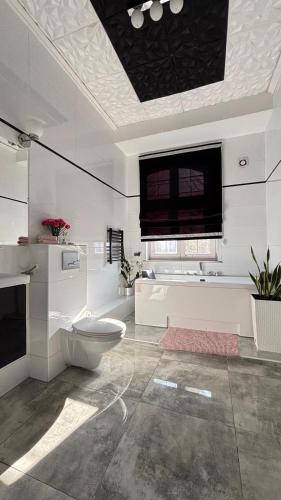 a white bathroom with a toilet and a window at Apartamenty Lux Chorzów in Chorzów