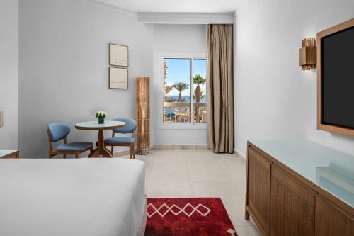 a hotel room with a bed and a table and a window at DoubleTree by Hilton Sharks Bay Resort in Sharm El Sheikh
