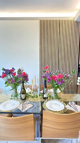 a dining table with two plates and flowers on it at Cozy Room in Modern Shared Apartment in Atalaya, Spain in Estepona