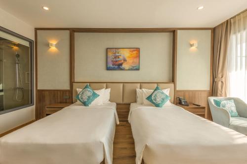a hotel room with two beds and a chair at Sunset Beach Resort and Spa in Phu Quoc