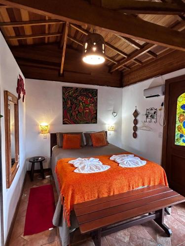 a bedroom with a bed with a bench in it at Chalés ANECUEM in Monte Verde