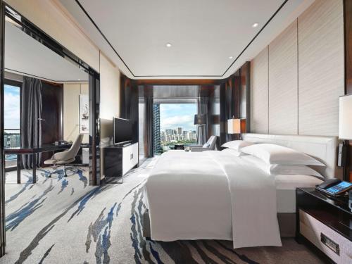 a bedroom with a large white bed and a desk at Hilton Shenzhen Shekou Nanhai in Shenzhen