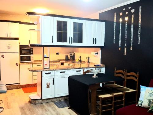 a kitchen with white cabinets and a black wall at Paradita del camino in Sarria
