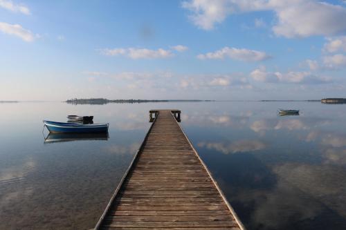 a wooden dock with a boat on the water at Villetta Airone in Birgi Vecchi