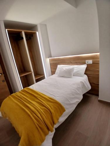 a bedroom with a white bed with a yellow blanket at Kalea Elysivm in Alcalá del Júcar