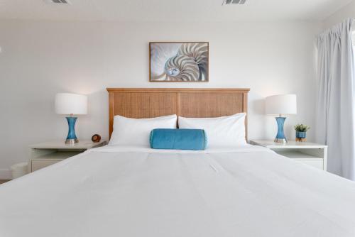 a large white bed with a blue pillow on it at Be a Nomad - Ocean Front Boutique Hotel in Jacksonville Beach