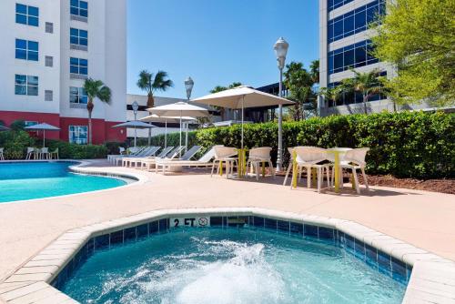 a swimming pool with chairs and a table and umbrella at Hilton Garden Inn Tampa Airport/Westshore in Tampa