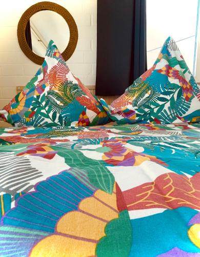 a bed with a colorful comforter and pillows on it at MiNe Hotel in Weilerswist