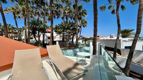 a balcony with chairs and a table and palm trees at Welooveyou Casa Ocean View in Costa Calma