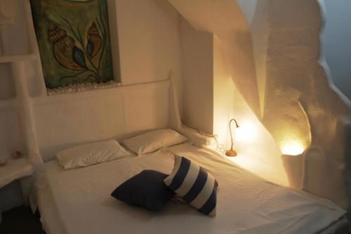 a white bed with a black and white pillow on it at Giannakas Studios in Platis Yialos Sifnos