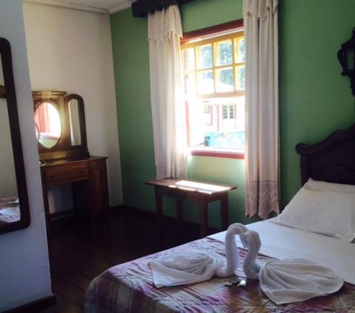 a bedroom with a bed with towels on it at Pousada Recanto Das Pedras in Tiradentes