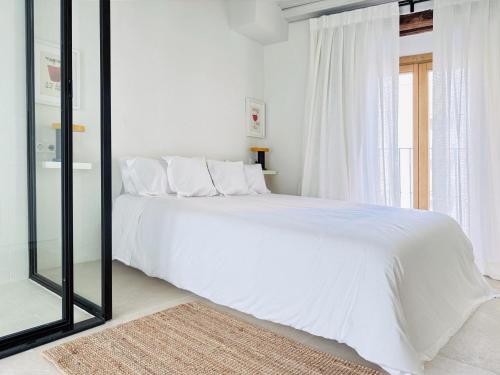 a bedroom with a white bed and a large window at Unika Homes Casa Bella in Seville
