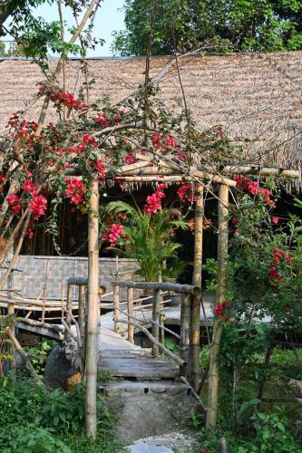 a garden with red flowers on a wooden bridge at Dong Que Homestay-Tours-Motorbike, Car rental, Hiking in Ha Giang